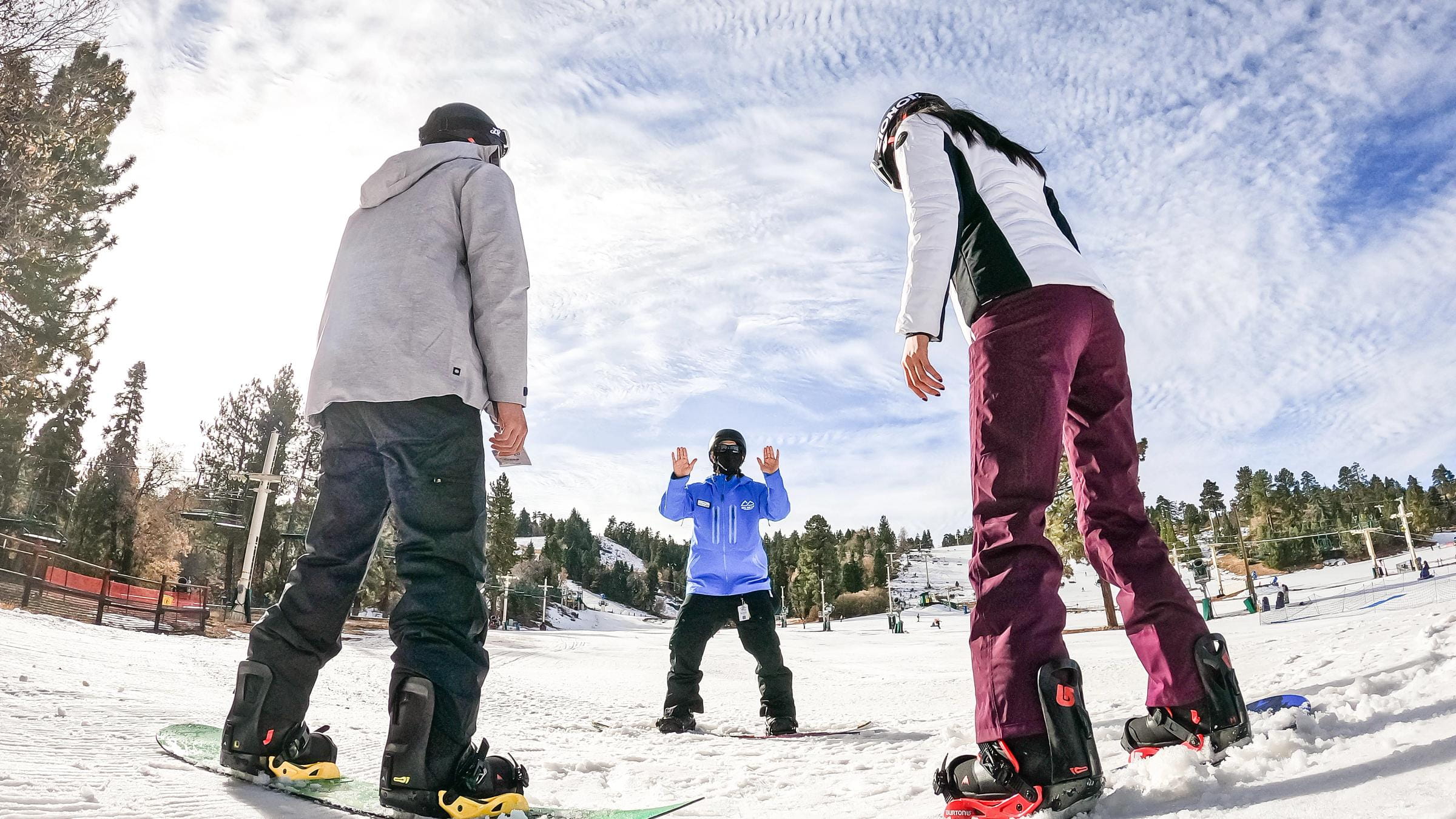 Two snowboarders facing snowboard instructor.
