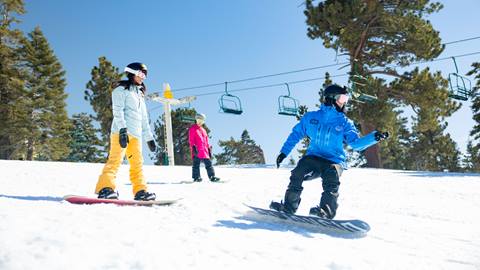 Mother and daughter taking a snowboard lesson with an instructor at Big Bear Mountain Resort