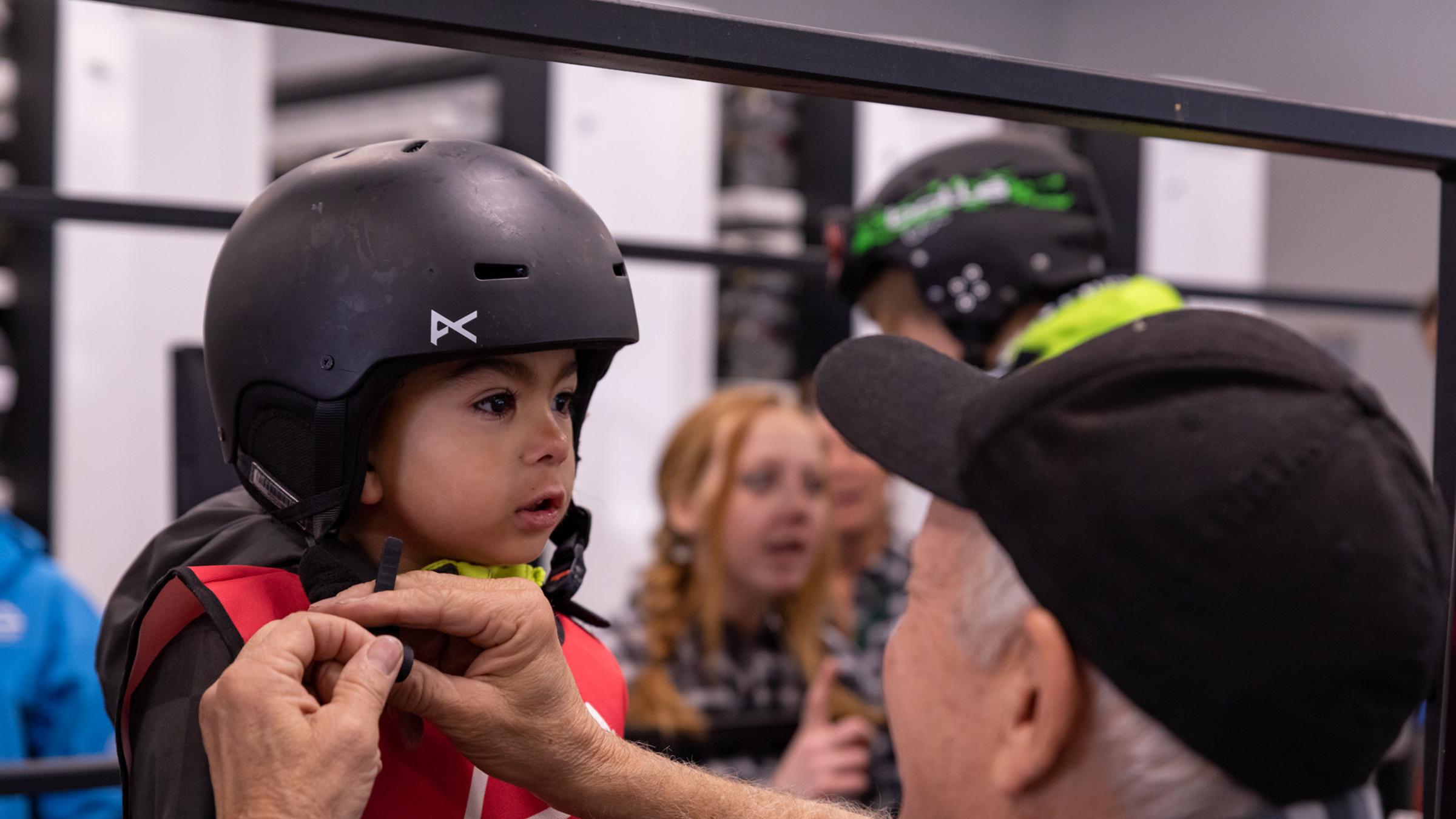 Child getting a rental helmet put on by staff.