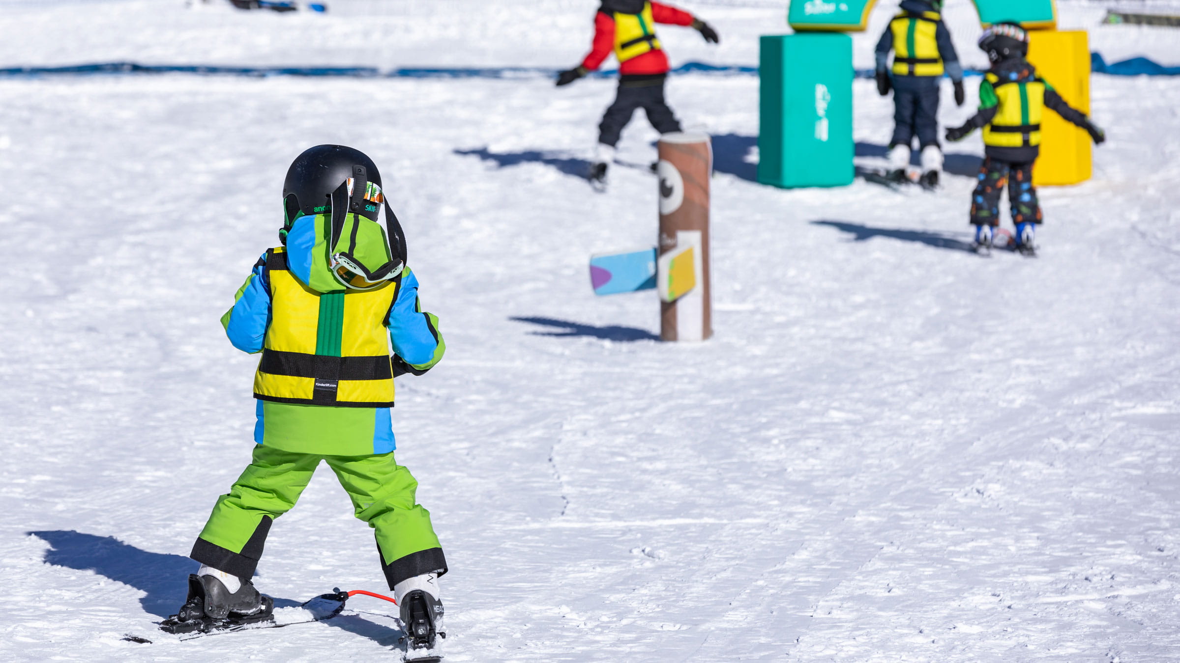 young skier wearing bright ski clothing taking a lesson down a ski slope