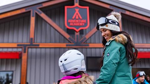 Mom taking daughter into the Adventure Academy for a ski lesson