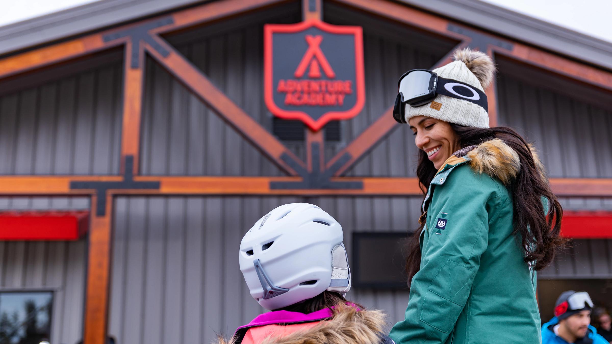Mom taking daughter into the Adventure Academy for a ski lesson