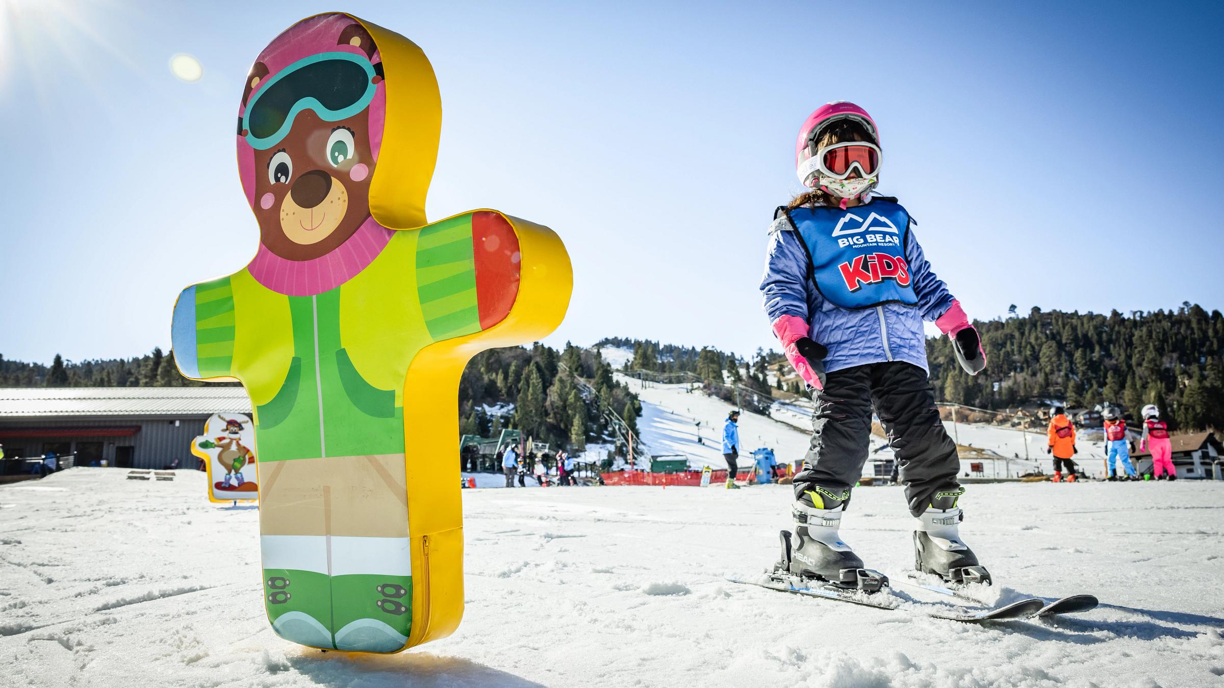Young skier taking next to a beary themed blow up for practice.