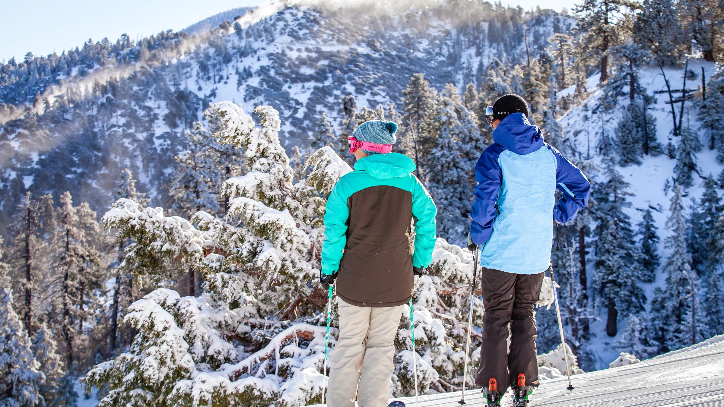 Male and female skiers overlooking the snowy mountains.