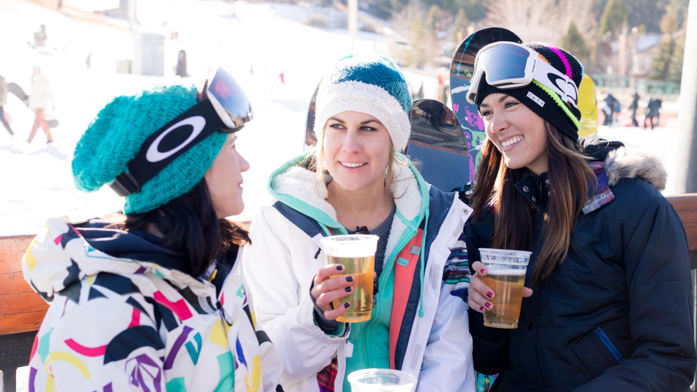 Three female snowboarders enjoying an adult beverage.