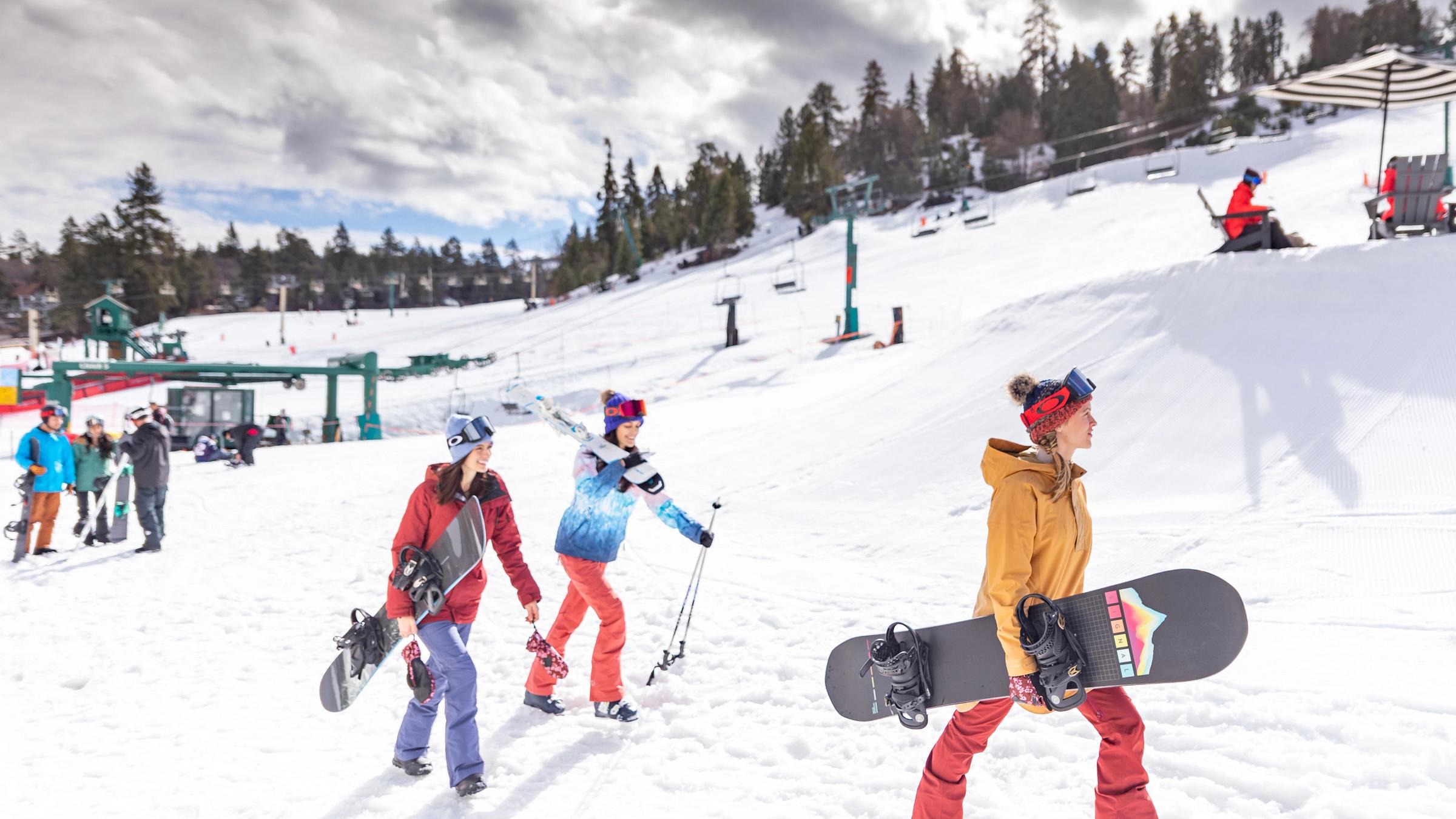 Group of snowboarding friends walking to chairlifts.