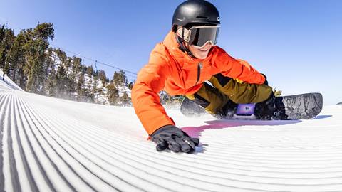 Snowboarder pointing at the board she wants in the rental shop