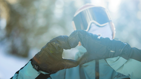 Snowboarder in full gear putting up heart hands