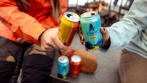 Two cans of Athletic Brewing cheersing