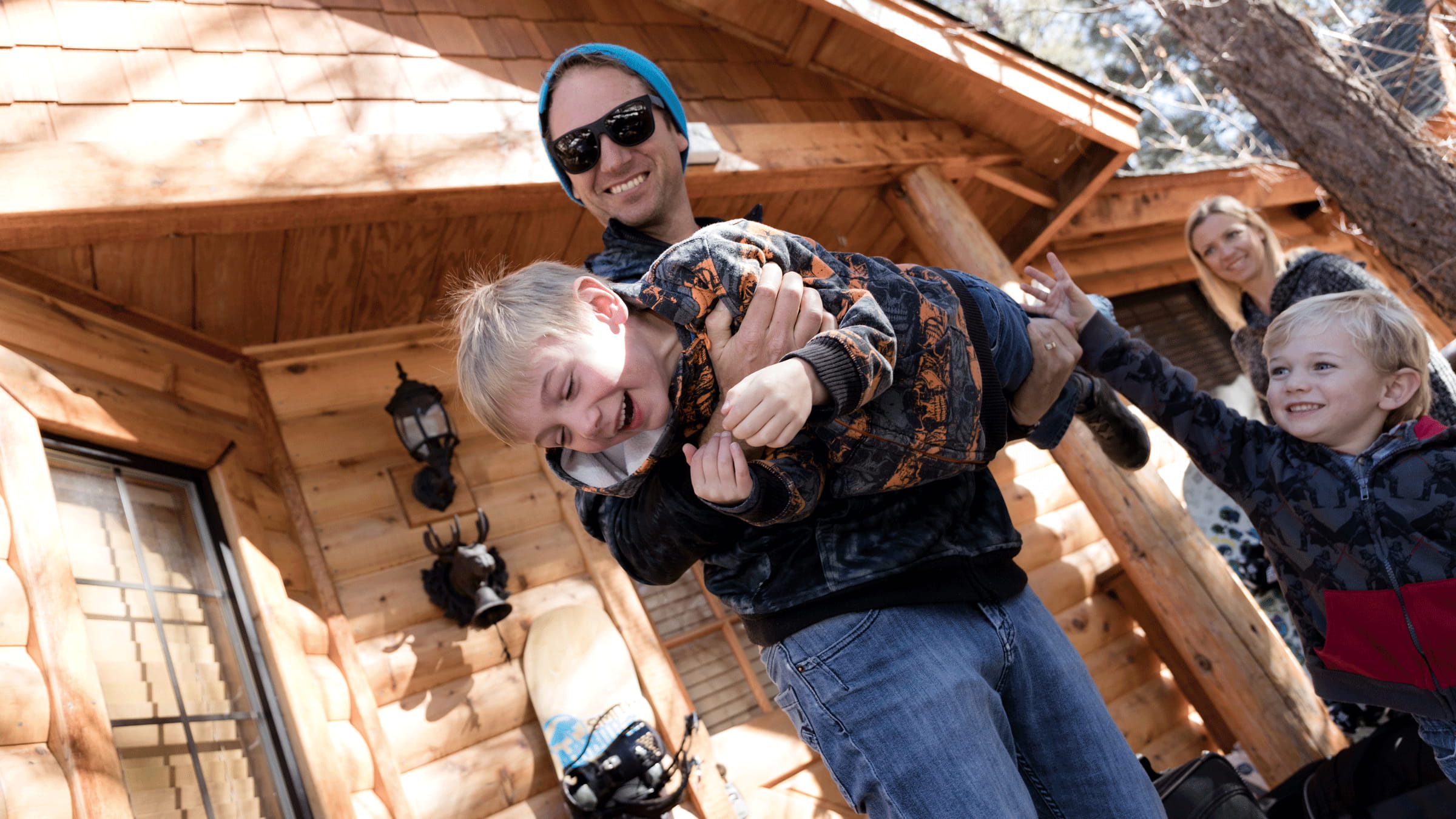 Family of 4 in front of their big bear lake lodging, dad carrying son