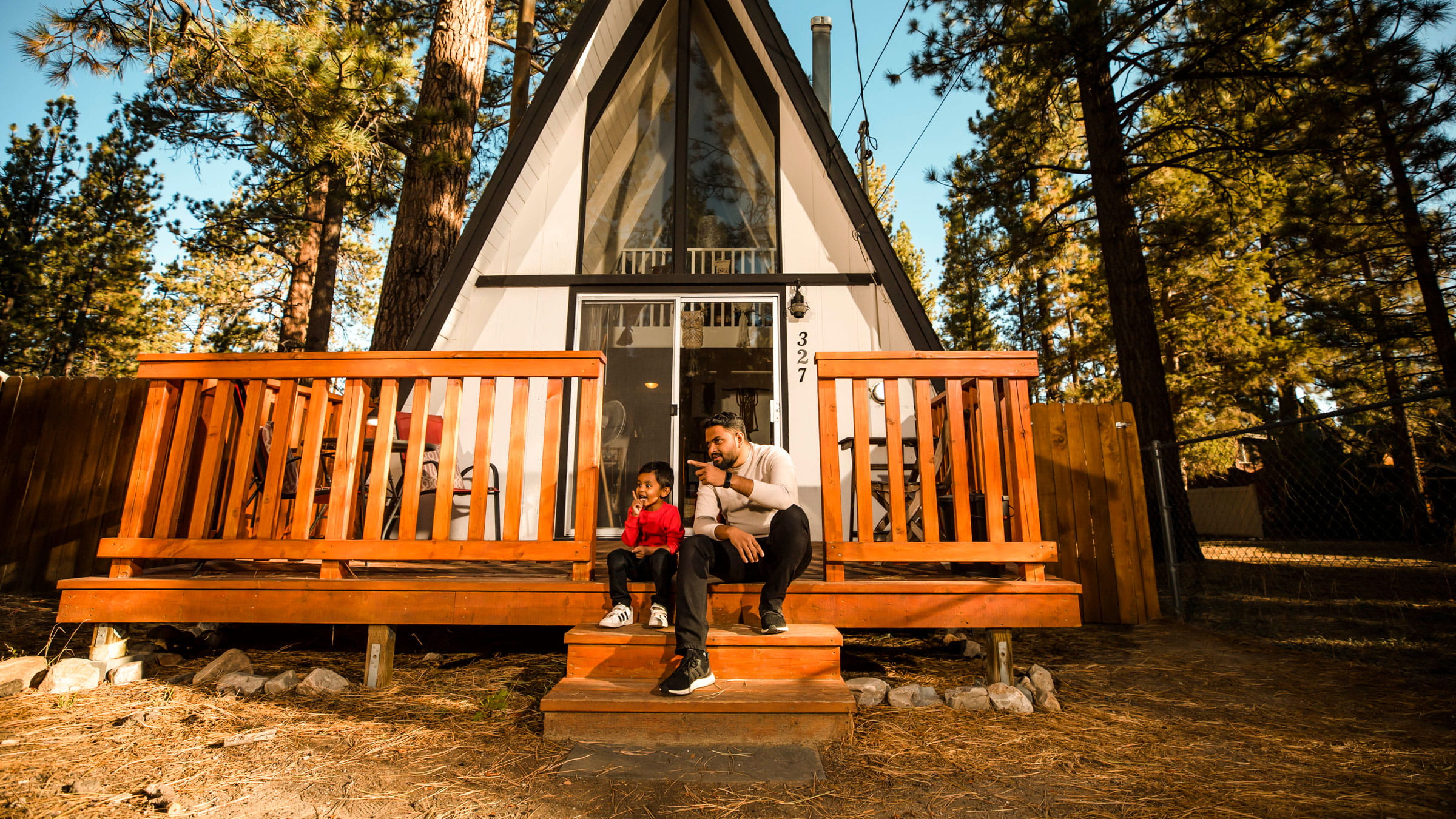 father and son sitting on a front deck stairs of an A frame house
