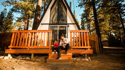 father and son sitting on a front deck stairs of an A frame house