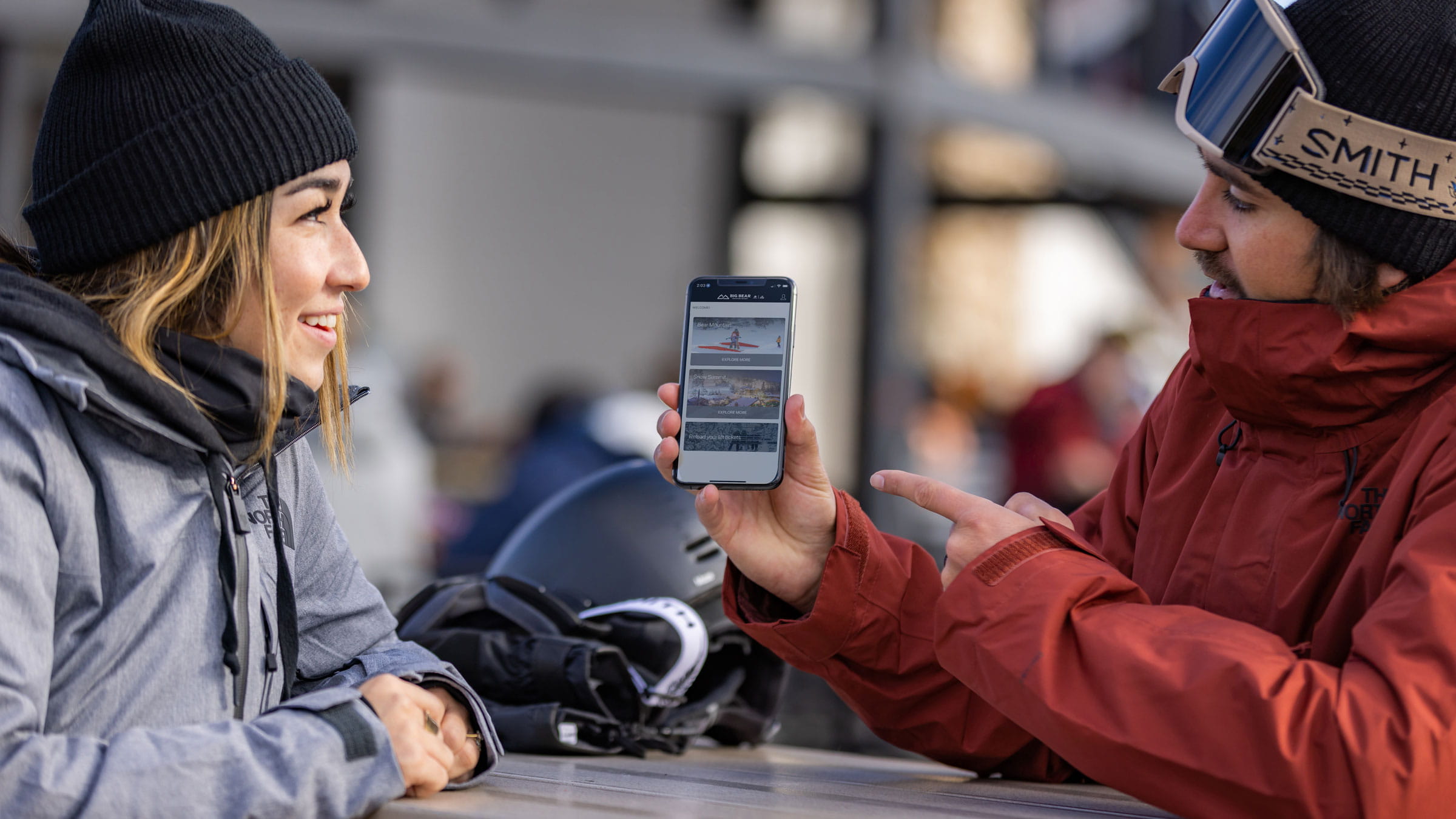 Snowboarder holding the BBMR mobile app and showing it to his girlfriend