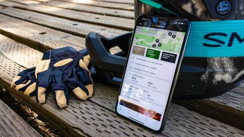 BBMR mobile app and phone leaning against MTB helmet with gloves