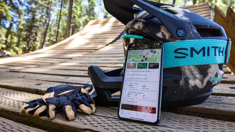 BBMR mobile app and phone leaning against MTB helmet with gloves