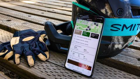 BBMR mobile app and phone leaning against MTB helmet with gloves