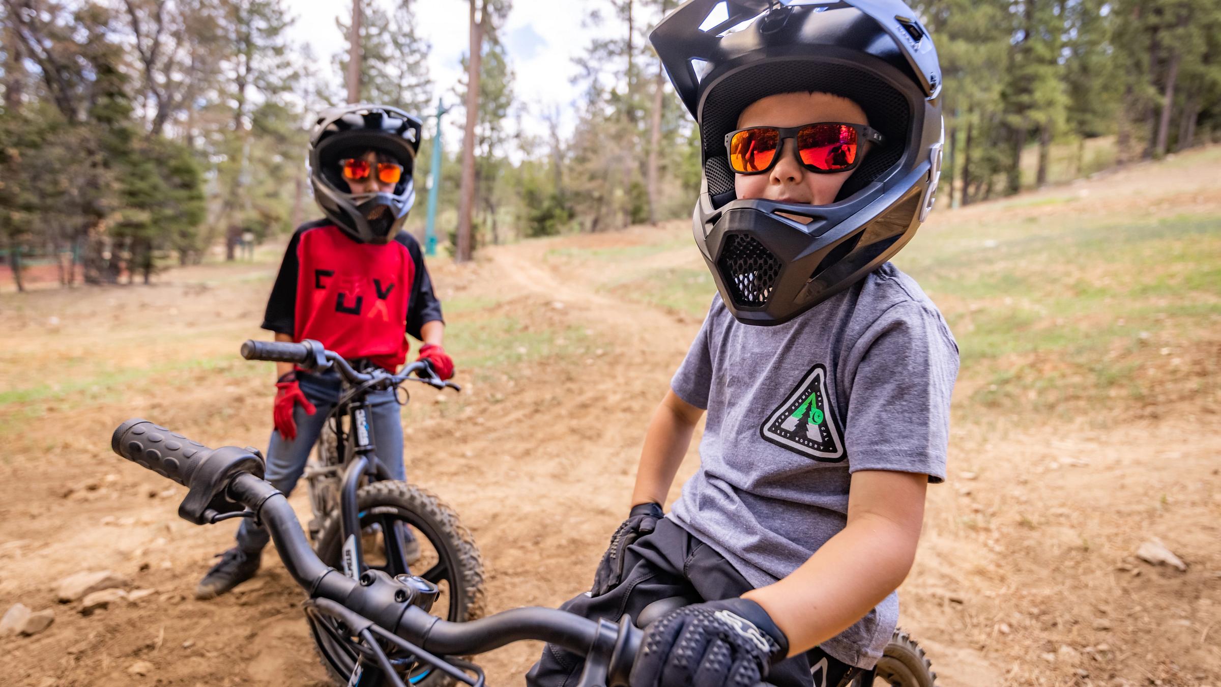 2 kids on electric bikes on smiling.