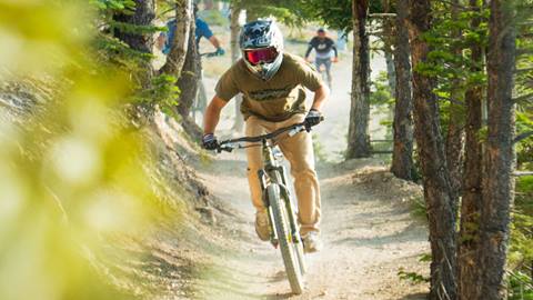 Mountain biker with two friends behind them in the summertime at Snow Valley bike park