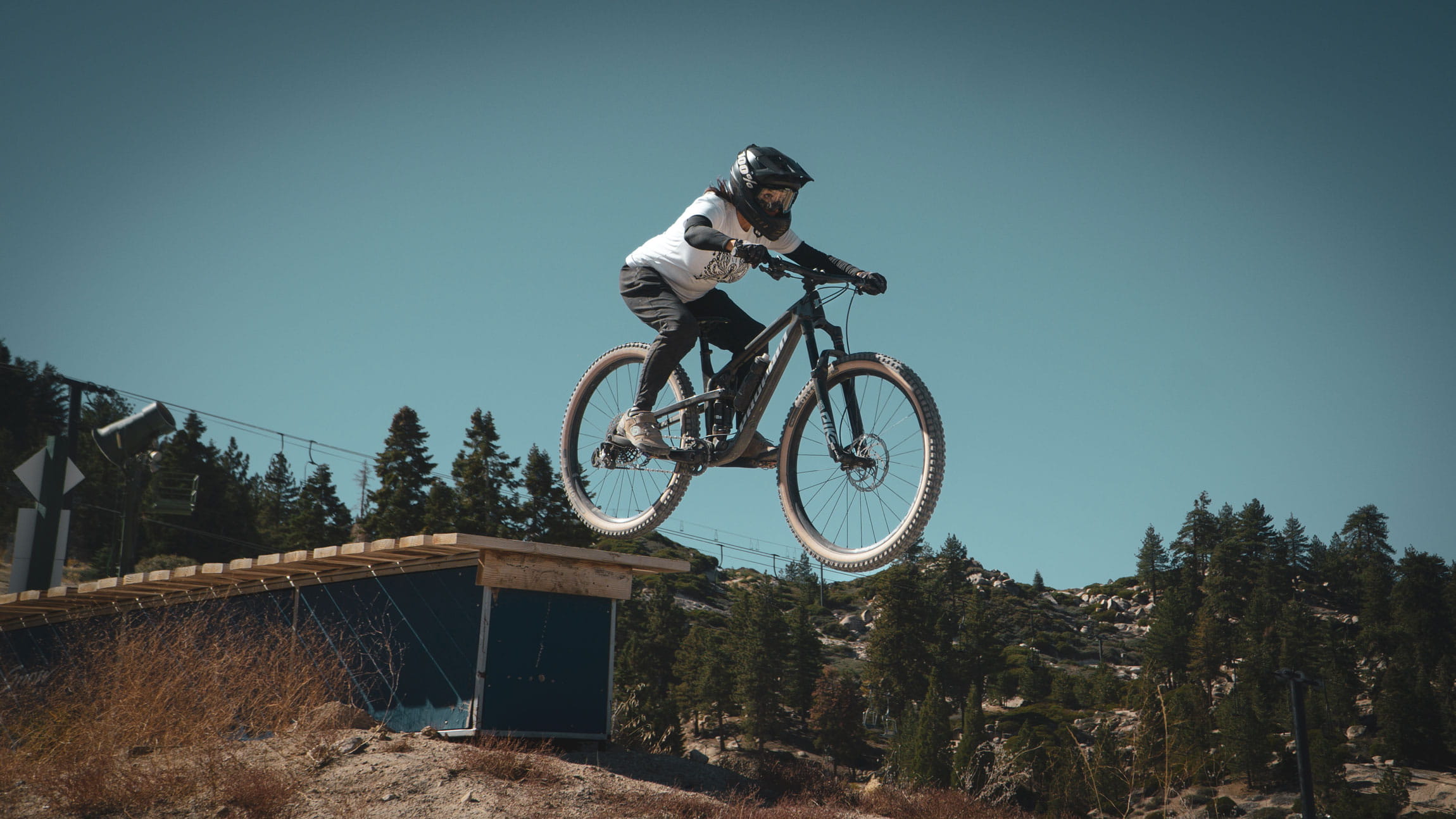 Mountain biker doing a jump trick on a mountain bike in the summertime at Snow Valley bike park