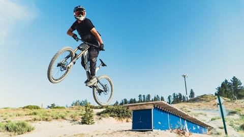 Mountain biker doing a jump trick on a mountain bike in the summertime at Snow Valley bike park