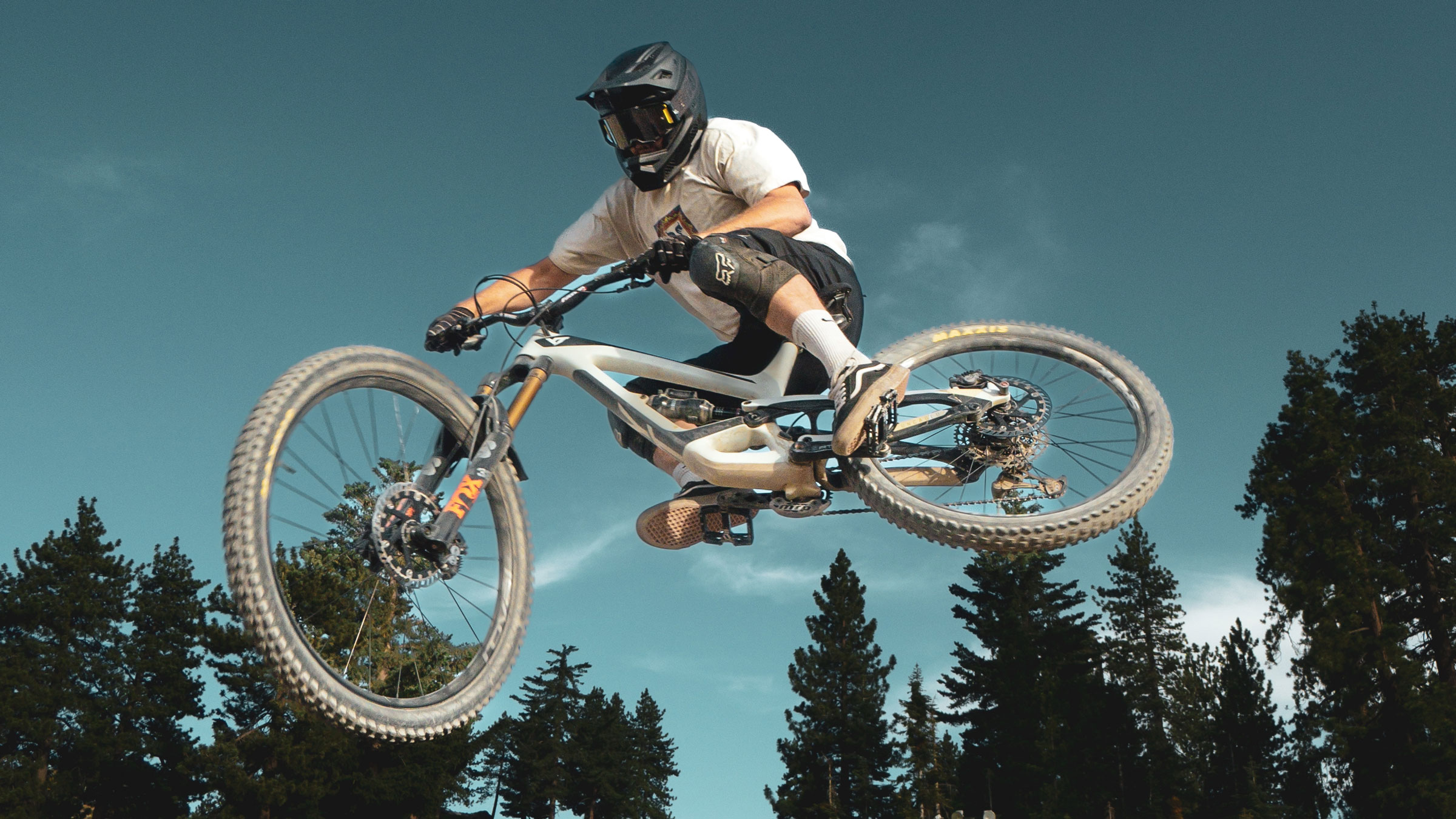 Mountain biker doing a jump trick on a mountain bike in the summertime at Snow Valley bike park
