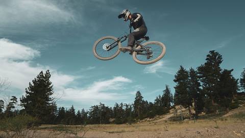 Mountain biker doing a jump trick on a mountain bike in the summertime at Snow Valley bike park