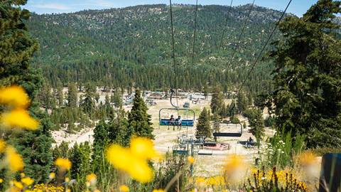 Snow Valley chairlift summer shot of two mountain bike riders on lift with main lodge in background