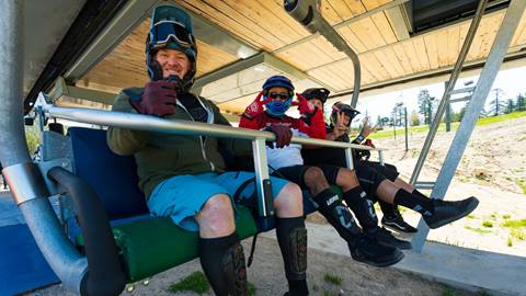 Four mountain bike riders loaded and seated on a chairlift at Snow Valley during the summer season.