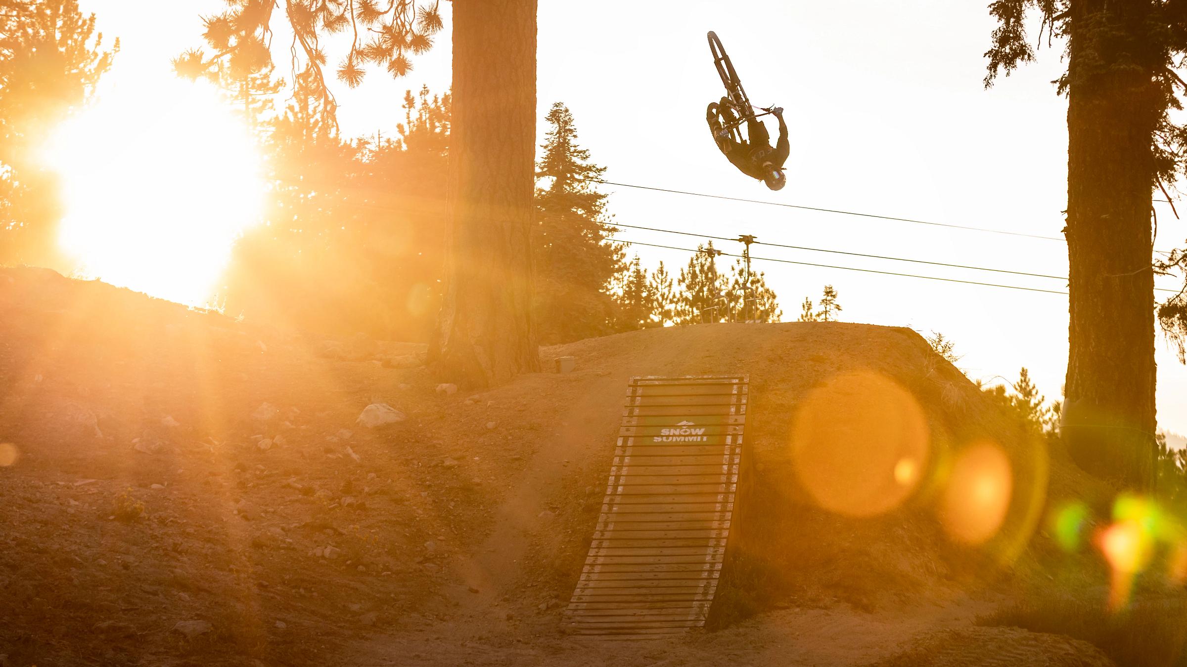 Mountain biker doing a backflip during golden hour.