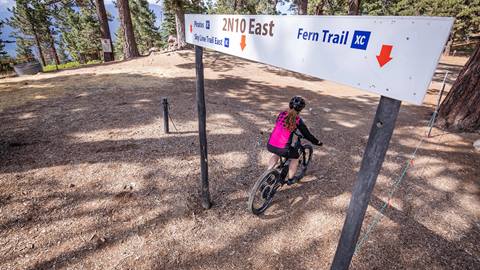 Mountain Biker riding through a trail sign