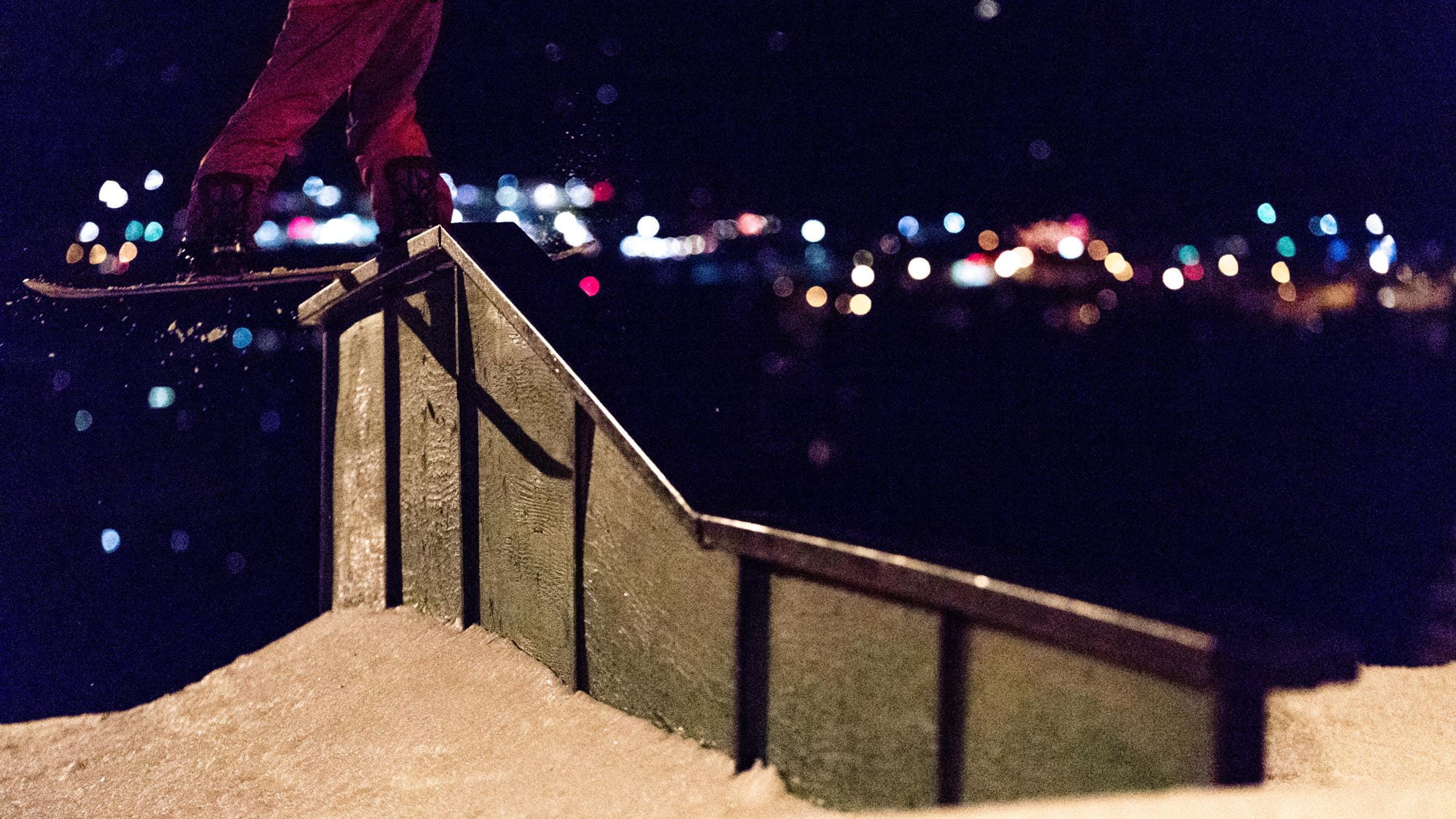 Snowboarder on a rail at night