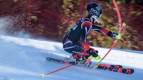 A teen ski racer weaving in and out of a red race gate on a slalom course at Snow Summit during the winter.