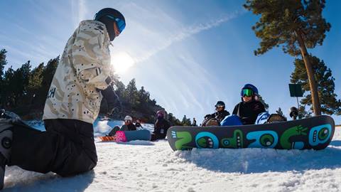 A Team Bear snowboard coach instructing his athletes while on the winter slopes.