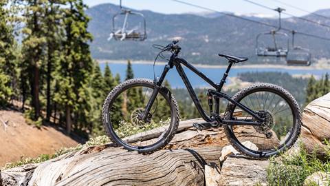 Rental mountain bike on a fallen tree at Snow Summit with a chairlift and Big Bear Lake in the background