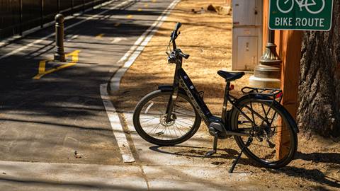 Trek eBike rental with bike stand down on the dirt next to a paved concrete bike route path.