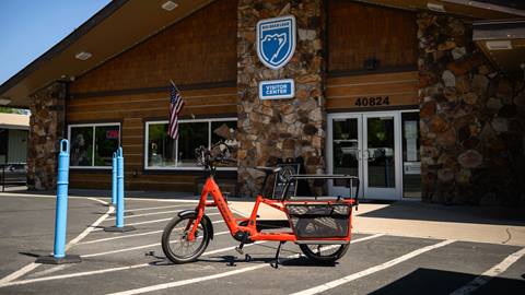 A red Trek branded eBike with a double seater kid carrier on the back.