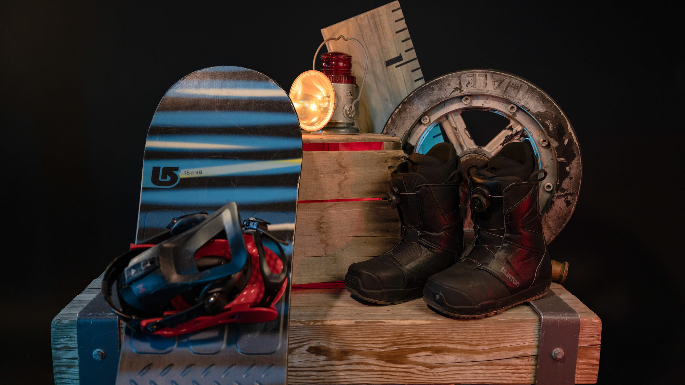 Snowboard with bindings and boots displayed against a wooden box