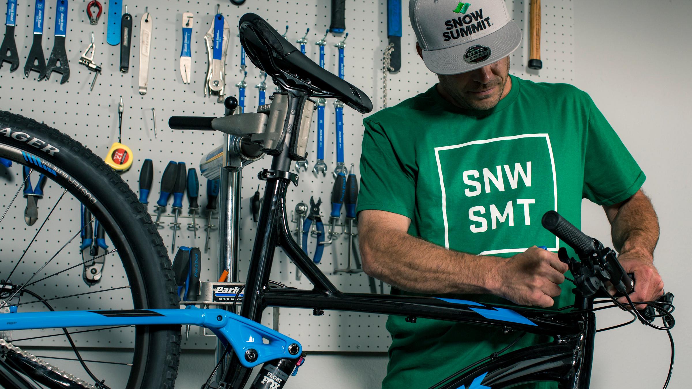 Guy fixing bike wearing a greens hirt