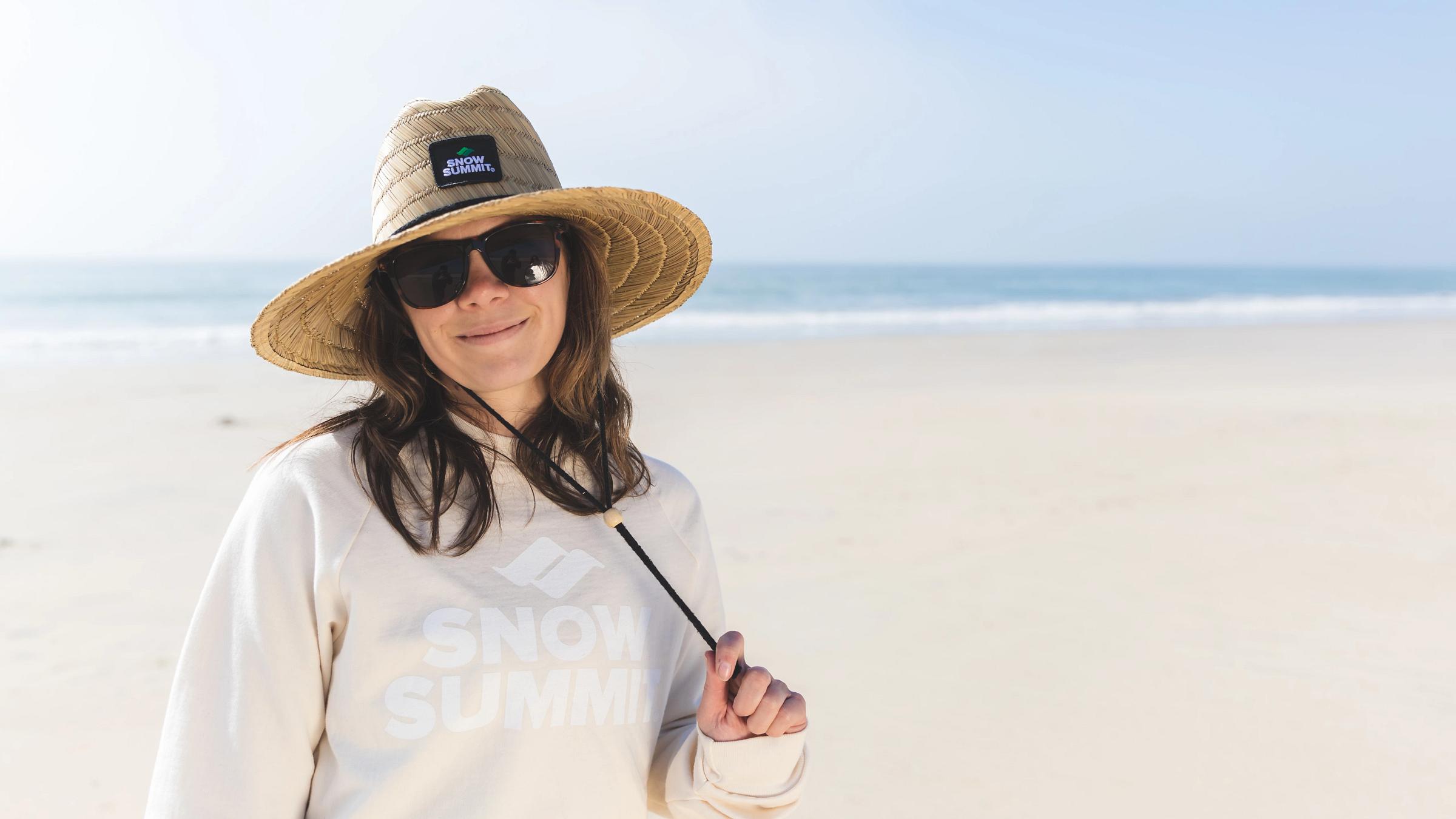 Female wearing sunglasses and a snow summit hat at the beach