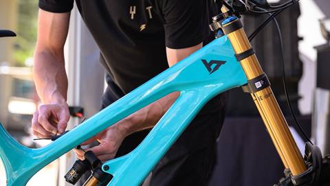 Close up of an adult working on a teal YT mountain bike.