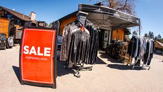 sale sign in front of a tent with a rack of clothes at snow summit in the summer time for the summer tent sale