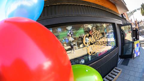 The outside Candy Corner store front in the base area of Snow Summit with a blue, red, and green balloon hanging in front of the store.