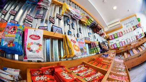 The inside of Snow Summit's Candy Corner store that has a variety of candy bags hanging on the walls and loose candy in wrappers in open drawers below.