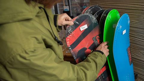 male looking through snowboards to buy