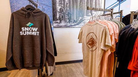 Snow Summit logo sweatshirt and Bear Mountain bear claw logo shirt displayed at retail store.