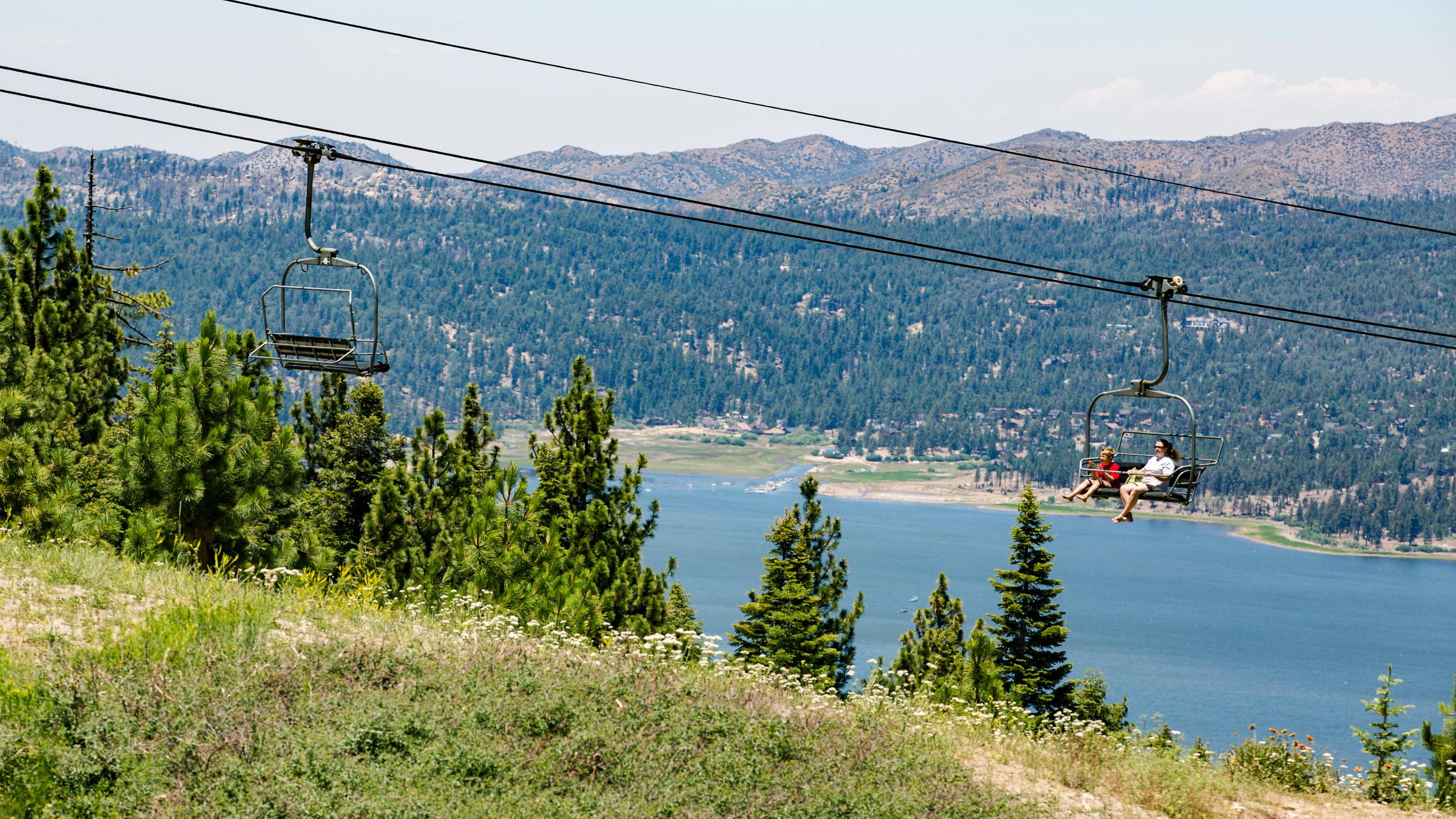 Guests riding a scenic sky chair with big bear lake in the background