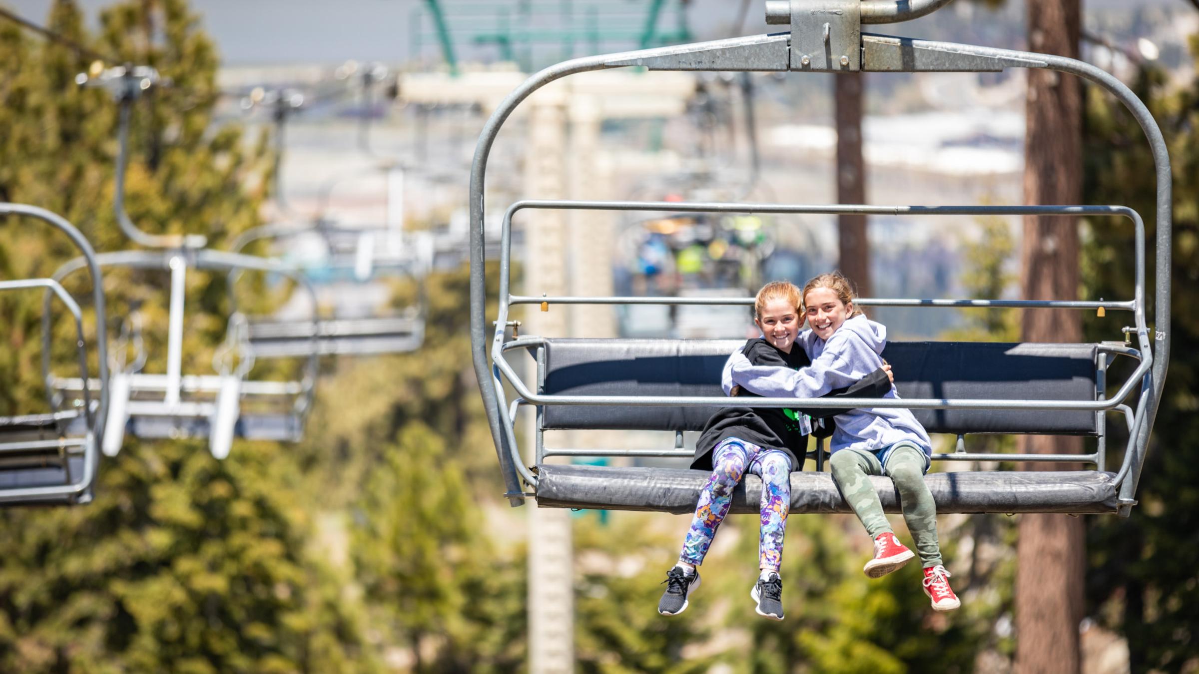 Two girls on a sky chair ride.