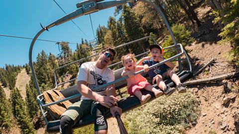dad and two young kids on the scenic sky chair ride at snow summit