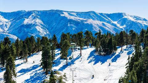A drone image of the top of Snow Summit after a snow fall in early winter on a bright blue sky day.