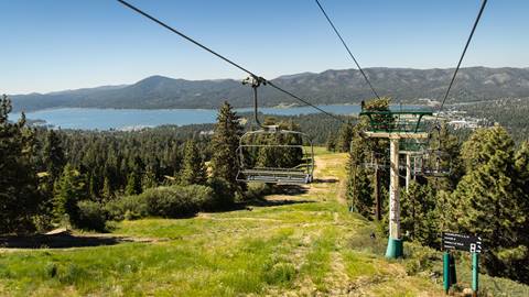 Summer chairlift shot of the green hill at Snow Summit and Big Bear Lake in the background